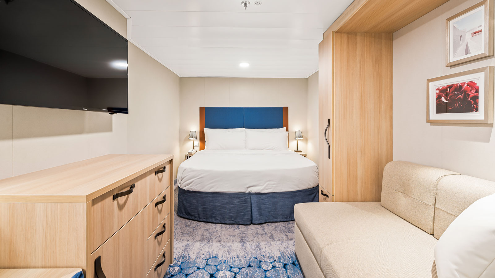 Interior stateroom aboard Utopia of the Seas with a queen bed, sofa, television, and built-in storage