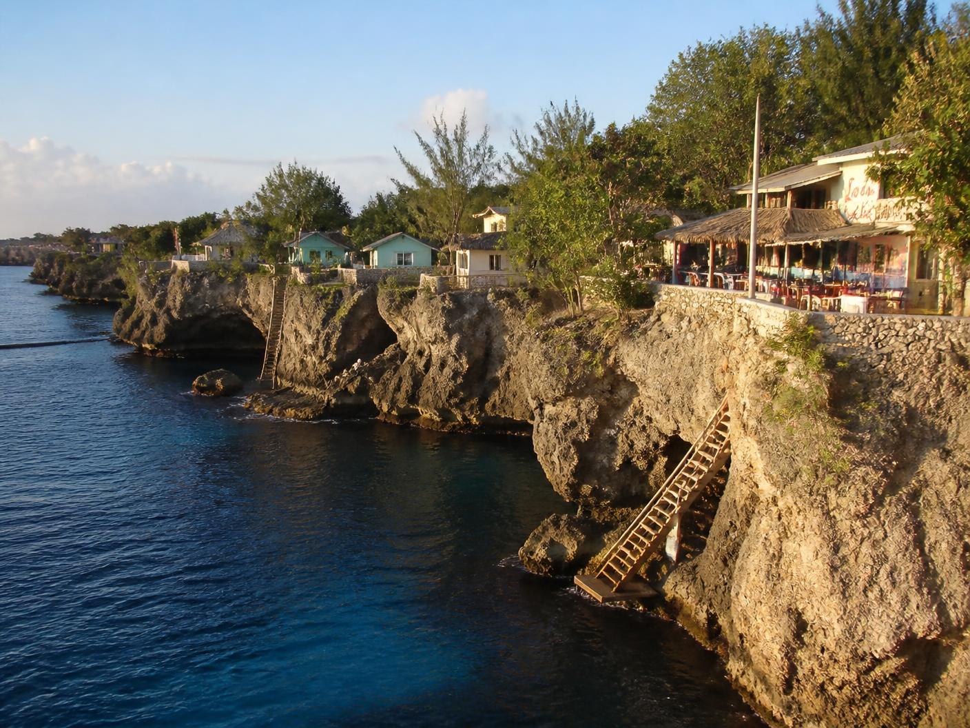 The limestone cliffs of Negril, Jamaica, with cliffside cottages, wooden ladders, and deep blue water below